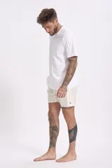 Short de baño color rosa con estampado de hojas y flores en tonos verdes, marrones y blancos.