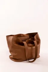 Bolso tote de cuero color tostado, con doble asa de hombro y diseño minimalista. Incluye un bolsillo separador extraíble.