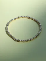 Pulsera elástica compuesta por cuentas redondas pequeñas de 3mm, con acabado dorado.