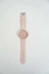Reloj de pulsera analógico color rosa pálido, con caja redonda y correa de cuero sintético.