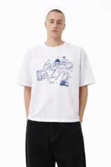 Remera blanca de corte holgado con cuello redondo y manga corta. Estampado frontal en azul que incluye el texto "DECO ALTO" y fragmentos de imágenes con paisajes o nubes.
