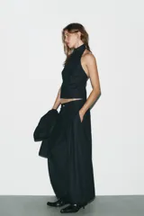 Pantalón bombacho de denim azul oscuro, tiro medio, con bolsillos laterales ocultos y de parche en la espalda. Presenta pinzas en la parte delantera y bajo abullonado con elástico.