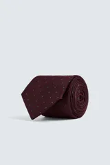 Corbata ancha color bordó con lunares azules, confeccionada en tejido de seda jacquard.