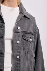 Campera de jean gris oscuro con cuello clásico, cierre frontal con botones metálicos, bolsillos con solapa en el pecho y corte holgado.