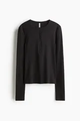 Remera ajustada de punto acanalado suave, color negro, con cuello redondo ribeteado en picot y tapeta de botones. Manga larga.