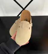 Zuecos color beige con plantilla de corcho y hebilla metálica ajustable.