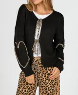 Saco largo color beige de tejido de punto con detalle de lazos con estampado animal print en el frente y en las mangas.