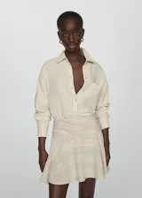 Camisa color crema de bambula con cuello camisero, diseño oversize, manga larga con puños abotonados, bolsillo de parche en la parte delantera y cierre delantero con botones.