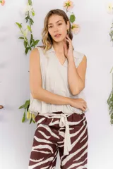 Blusa color beige claro, sin mangas, con cuello tipo camisa y corte holgado con elástico en la cintura.