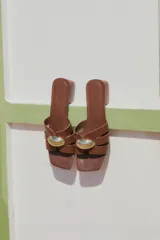 Sandalias de cuero color chocolate con taco bloque bajo, punta cuadrada y tiras cruzadas con detalle metálico dorado.