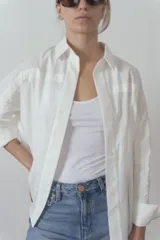 Camisa blanca de manga larga con cuello clásico y cierre frontal con botones.