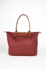 Bolso tote de nylon color gris topo, con asas fijas símil cuero color marrón. Tiene cierre superior y dos bolsillos internos.