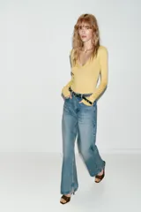 Jeans de tiro alto color azul claro, con cinco bolsillos y pernera recta que se estrecha hacia el tobillo. Incluye un cinturón negro con detalles metálicos.