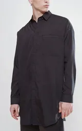 Camisa negra de manga larga con bolsillo ojal en el delantero, cartera escondida y calce oversize.