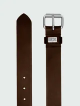 Cinturón de cuero marrón oscuro con hebilla metálica plateada de doble argolla y textura rugosa. Incluye un pasante de cuero con placa metálica grabada con el logo de Diesel.