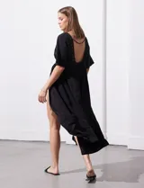 Kaftan blanco largo con mangas cortas y abertura central. Presenta apliques de puntilla en el escote, cintura y ruedo. Se ata en la cintura con un lazo.