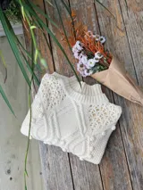 Sweater tejido grueso color rosa, con cuello alto, mangas largas y diseño trenzado con detalles de pompones.