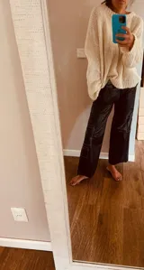Pantalón cargo de cuero negro con costuras blancas en contraste, tiro medio y corte holgado.