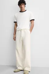 Pantalón color crema de corte amplio, con cintura elástica ajustable con cordón, bolsillos laterales y trasero, cierre frontal con cremallera y botón.