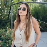 Chaleco corto color crema con escote en V, sisa redonda y cierre delantero con botones.