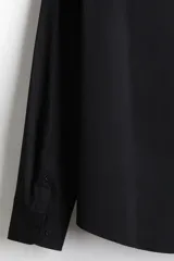 Camisa negra de manga larga con cuello italiano y tapeta lisa. Presenta un corte ajustado (slim fit) y bajo redondeado.