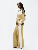 Pantalón de jogging color beige con una franja vertical blanca en el lateral.