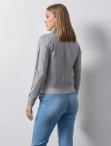 Cardigan color beige en tejido jacquard, con cuello con solapa y abertura central con cierre. Delantera con bolsillos simulados.