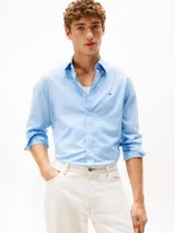 Camisa celeste de algodón Oxford con corte regular y mangas largas. Tiene cuello abotonado, cierre con botones y logo de Tommy Hilfiger bordado en el pecho.