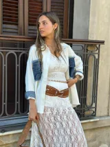 Sobrecamisa blanca de denim con cuello camisero, cierre frontal con botones a presión, mangas largas con puños abotonados, dos bolsillos de parche en el pecho con solapa y detalles desgastados en los bordes.