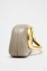Bolso formato caja color crema con asa de cadena dorada para usar como bandolera. Cierre metálico dorado.