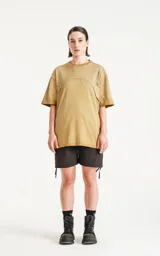 Remera oversize de algodón, color mostaza con efecto batik artesanal. Presenta costuras decorativas arqueadas que unen el cuello con los hombros y el torso.