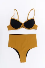 Conjunto de bikini negro y dorado, con corpiño triangular y bombacha clásica con cintura alta.