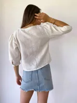 Blusa de muselina color crudo, con mangas tres cuartos abullonadas y botones de madera.