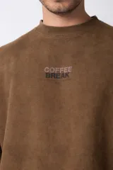 Buzo marrón de algodón rústico con lavado gastado y cuello redondo. Estampa frontal con la frase "Coffee Break". Corte oversize.