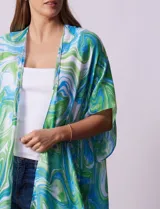 Kimono tejido con estampado abstracto en tonos verde, azul y blanco. Tiene mangas cortas amplias y terminación con borlas verdes en el ruedo.