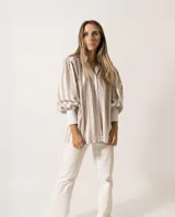 Camisa a rayas verticales color beige y blanco, de corte holgado, con cuello camisero y mangas largas abullonadas con puños abotonados.