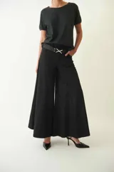 Pantalón palazo negro de tiro medio y largo hasta los tobillos.