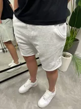 Bermuda deportiva gris claro de algodón con bolsillos laterales y logo estampado en la pierna.