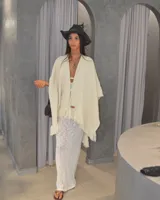 Ruana color crema de tejido grueso con flecos en el borde inferior.