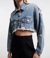 Campera cropped de jean celeste con cuello solapa, cierre frontal con botones, mangas largas, barra deshilachada con flecos y detalles de roturas.