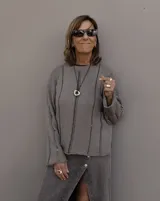 Collar con dije dorado irregular con agujero central, colgando de cordón negro ajustable.