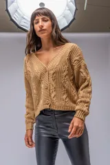 Saco color beige de tejido de punto trenzado, con escote en V y cierre frontal con botones marrones.