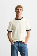 Camiseta azul marino de corte recto, con cuello redondo y mangas cortas. Presenta ribete blanco en cuello y mangas.