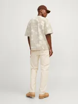 Camiseta de manga corta y cuello redondo, con fit oversize. Presenta un estampado tipo tie-dye o acid wash en tonos beige y crema.