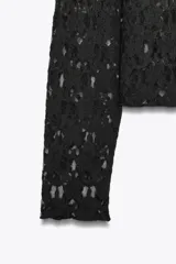 Camiseta negra de encaje con cuello alto y mangas largas.