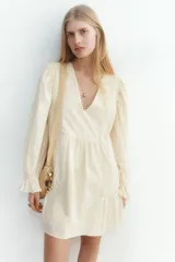 Vestido corto color crema en tejido liviano de algodón con inserciones de encaje, escote en V y mangas largas abullonadas con elástico en la muñeca y puños acampanados.