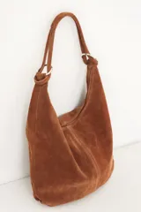 Bolso tipo hobo de cuero color visón con cierre superior y correa de hombro.