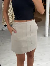 Pollera corta negra de ecocuero, con cortes y detalles de bolsillos grandes.