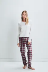 Pijama de algodón compuesto por un pantalón largo a cuadros rojos, negros y blancos, con cintura elástica ajustable con cordón, y una remera blanca de manga larga con cuello redondo y botones.