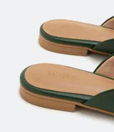 Zapatilla mule color verde oscuro, con puntera redonda, bridón metálico dorado, tachas doradas y suela marrón.